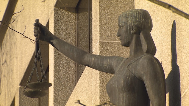 Une statue féminine tient une balance dans la main droite devant le palais de justice à Vancouver.