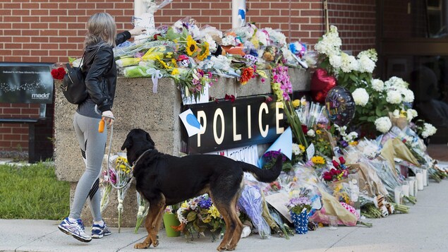 Une dame dépose des fleurs devant le poste de police de Fredericton. Une dame dépose des fleurs devant le poste de police de Fredericton.