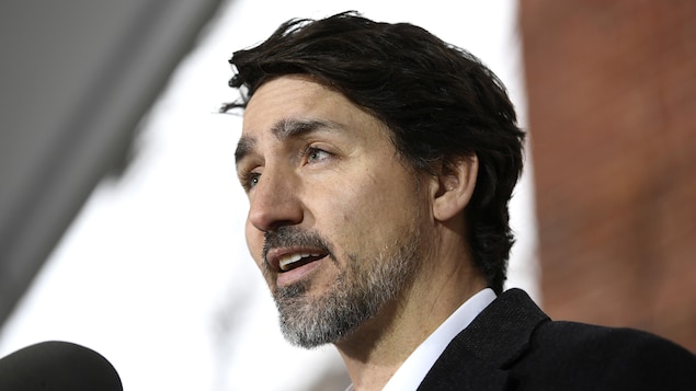 Justin Trudeau, de profil, parle dans un micro.