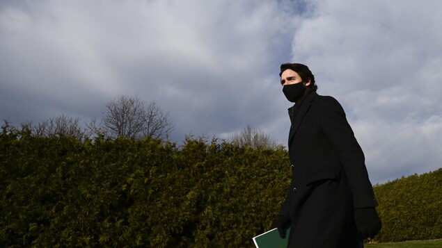 Il porte un masque et marche à l'extérieur.