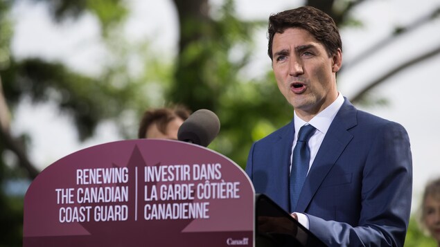 Le premier ministre Justin Trudeau s'adresse aux médias à l'extérieur avec en arrière-plan un grand arbre.