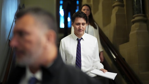 Justin Trudeau regarde vers le bas en descendant des marches.