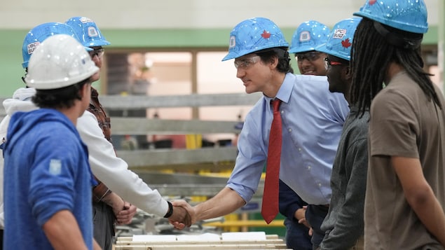 Justin Trudeau (au centre) rencontre des charpentiers avant de parler de nouvelles solutions en matière de logement au centre de formation CCAT à Woodbridge, en Ontario, le vendredi 12 avril 2024.