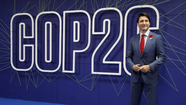 Justin Trudeau pose près d'une affiche de la COP26.