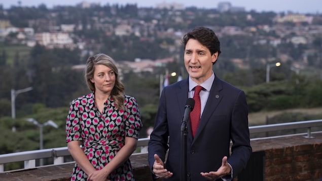 Justin Trudeau parle dans un micro. Mélanie Joly est à côté de lui.