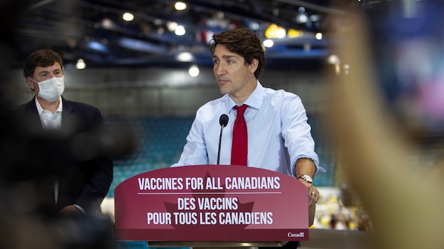 El primer ministro Justin Trudeau en un podio con el ministro Dominic Leblanc en un coliseo.