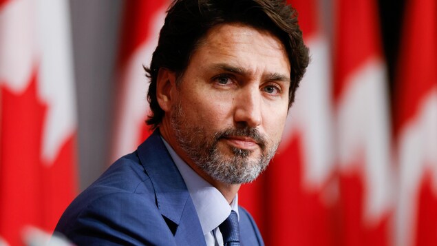 Justin Trudeau devant une série de drapeaux du Canada. 