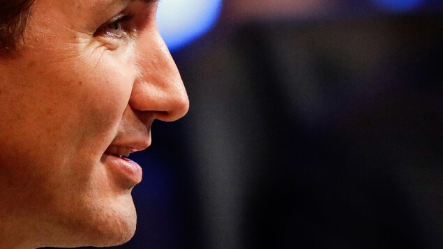 Gros plan sur le visage vu de côté de Justin Trudeau avec en arrière-plan un fond flou.