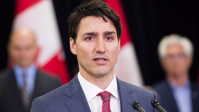 Justin Trudeau, l'air sérieux, est derrière deux micros. Justin Trudeau, l'air sérieux, est derrière deux micros.