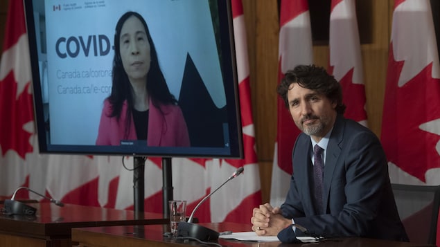Prime Minister Justin Trudeau and, on a television screen, Chief Public Health Officer Dr. Theresa Tam.