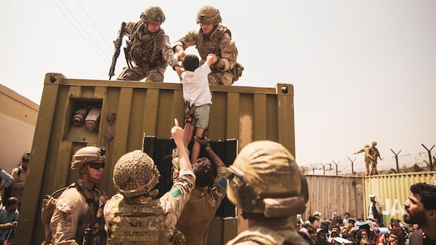 一个孩子在士兵的帮助下爬上军车。