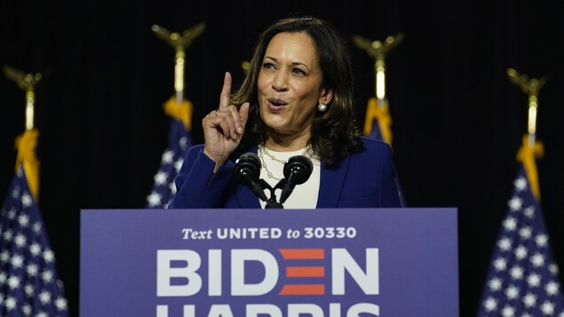 Kamala Harris parle sur une tribune l'index levé.