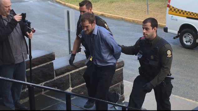 L'accusé entouré de deux policiers de la Sûreté du Québec L'accusé entouré de deux policiers de la Sûreté du Québec