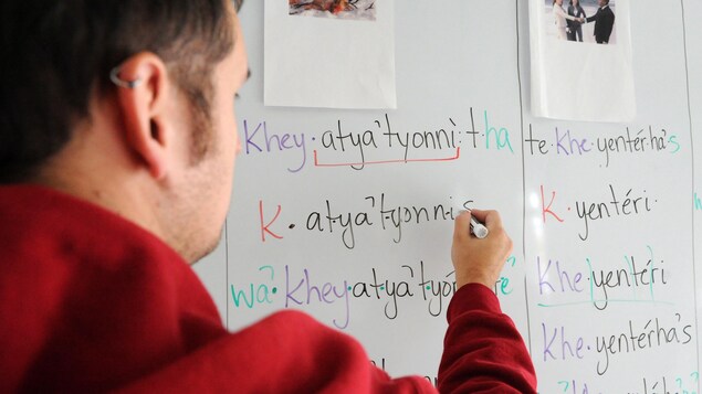 Un enseignant écrit en langue kanien'kéha (mohawk) sur un tableau blanc.