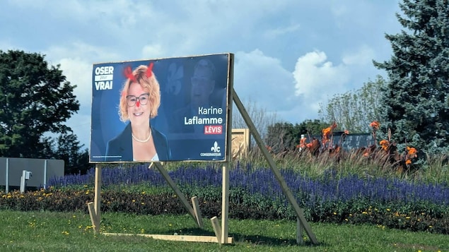 Une pancarte électorale où des cornes ont été ajoutés à la photo de la candidate, Karine Laflamme.