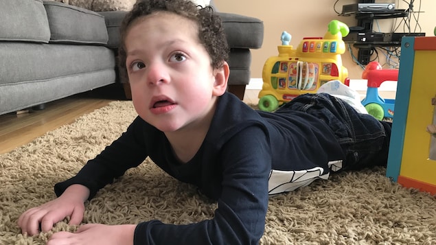 Kayden Kot, 6 ans, couché par terre sur le ventre, dans le salon de sa résidence à Saskatoon