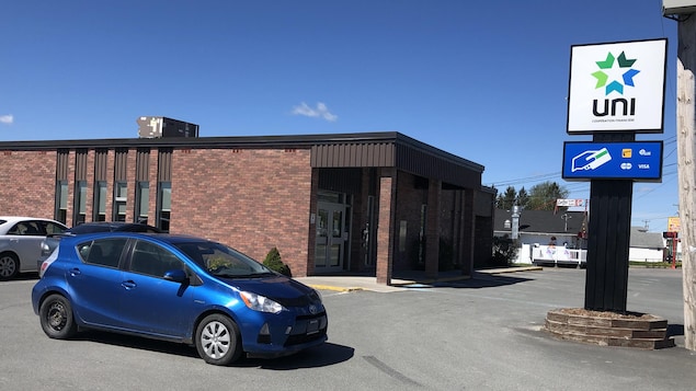 Trois voitures garées devant un petit édifice recouvert de briques.