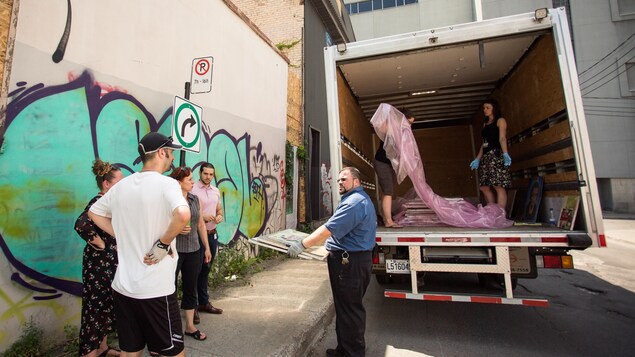 Des employés de l'ÉTS rassemblent les toiles de Kellner dans un camion de transport.