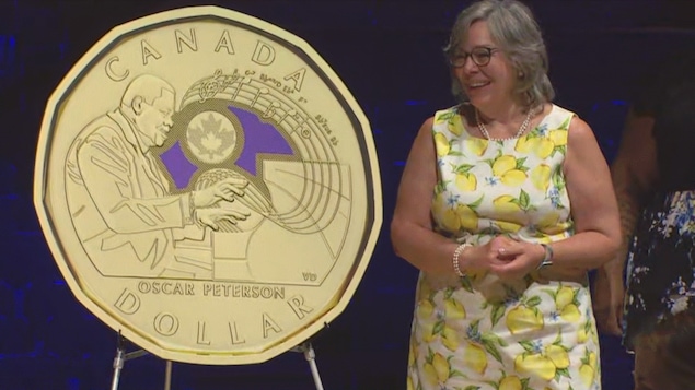 Una mujer admira una gran moneda en la efigie de Oscar Peterson.