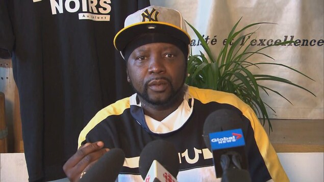 Un homme portant une casquette parle aux médias.