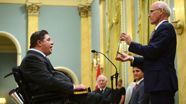 Kent Hehr, assis dans son fauteuil roulant, prête serment à titre de ministre des Sports et des Personnes handicapées sous l’oeil du premier ministre Justin Trudeau.