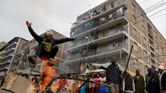 Un partisan de Raila Odinga saute au-dessus d'une barricade dans le bidonville de Mathare. Un partisan de Raila Odinga saute au-dessus d'une barricade dans le bidonville de Mathare.