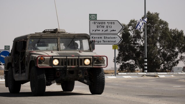 Un véhicule israélien roule devant une pancarte de la ville de Kerem Shalom.