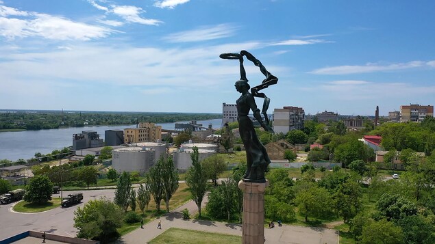 Vue aérienne de la ville, incluant une statue qui la surplombe. Des véhicules militaires sont visibles. 