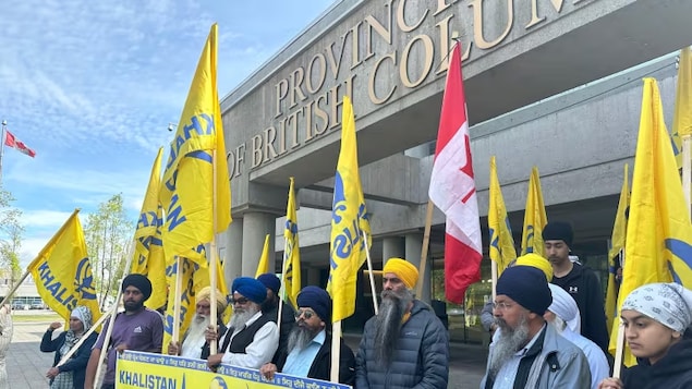 Protesters stand outside a courthouse in Surrey, B.C., prior to an appearance of one of four men charged with murder in the death of Sikh leader Hardeep Singh Nijjar.