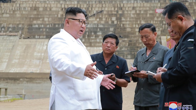 Un Asiatique s'adresse à d'autres hommes, l'air sérieux. Les autres hommes prennent des notes sur des calepins.