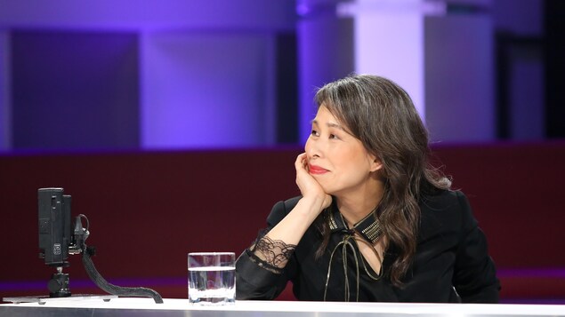 La femme regarde sur le côté en appuyant la tête sur sa main.