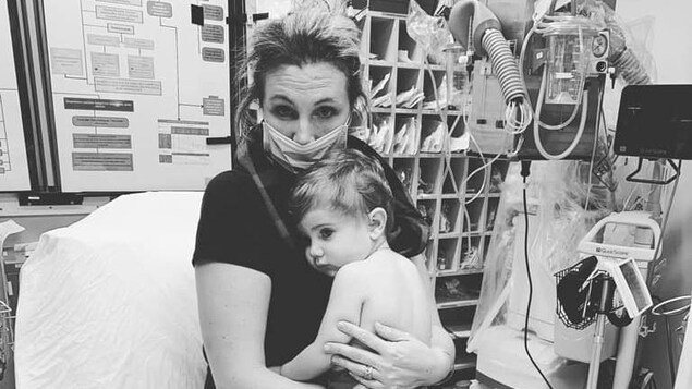 Une femme tient son fils dans ses bras dans un lit d'hôpital.