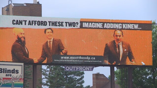 Un panneau où apparaissent le chef du NPD du Manitoba, Wab Kinew, le chef du NPD du Canada, Jagmeet Singh, et le premier ministre Justin Trudeau.