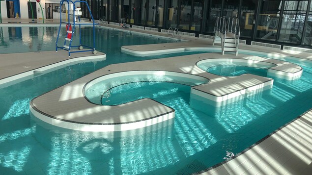 On voit une piscine intérieure. Elle comporte une partie rectangulaire et une partie en serpentin avec des bassins à remous.
