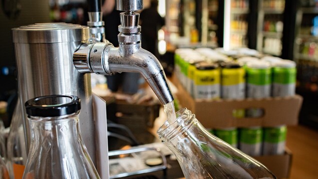 Une personne remplit une bouteille vide de kombucha en fût. Une personne remplit une bouteille vide de kombucha en fût.