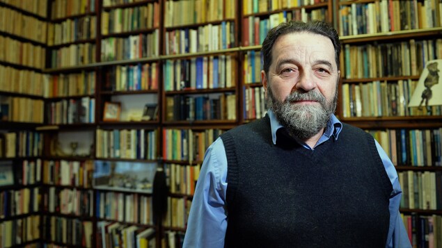 L'homme est debout devant une immense bibliothèque remplie de livres. L'homme est debout devant une immense bibliothèque remplie de livres.