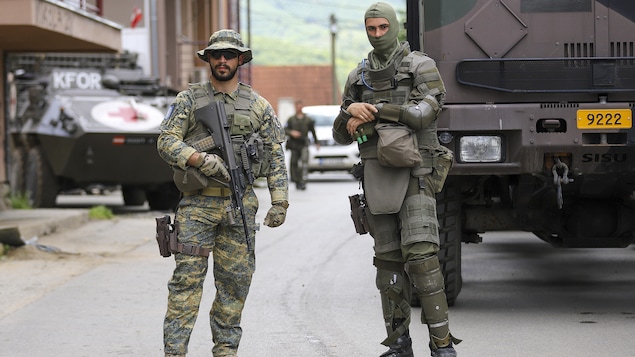 Deux soldats debout devant des véhicules militaires