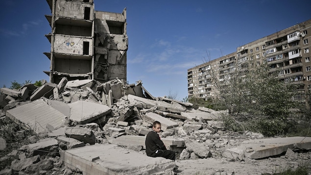 Un enfant ukrainien est assis sur un débris de béton tombé d'un immeuble démoli.