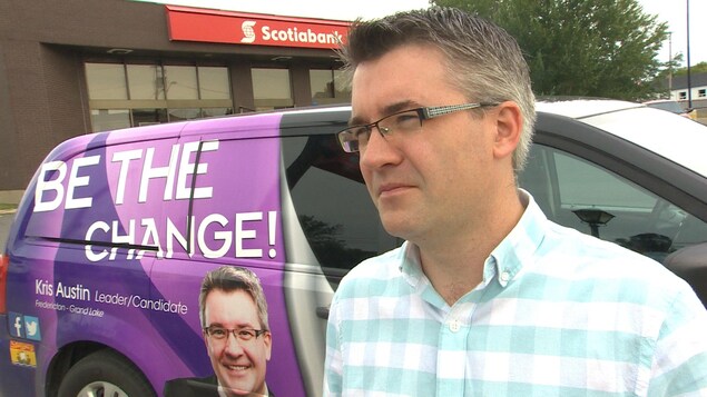 Kris Austin se tient debout devant son véhicule de campagne. Kris Austin se tient debout devant son véhicule de campagne.