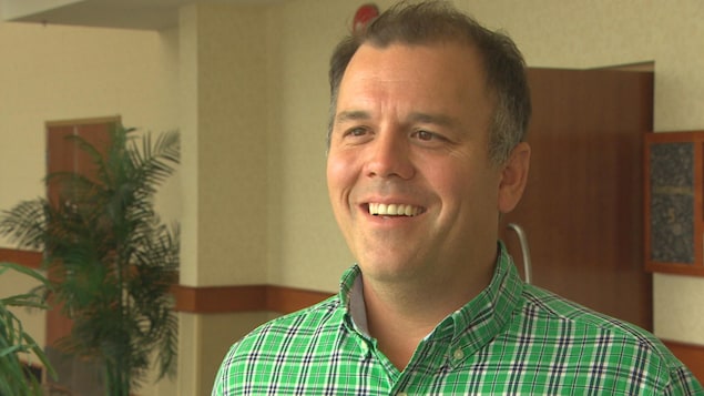 Un homme qui porte une chemise verte, souriant, en entrevue avec Radio-Canada. Un homme qui porte une chemise verte, souriant, en entrevue avec Radio-Canada.