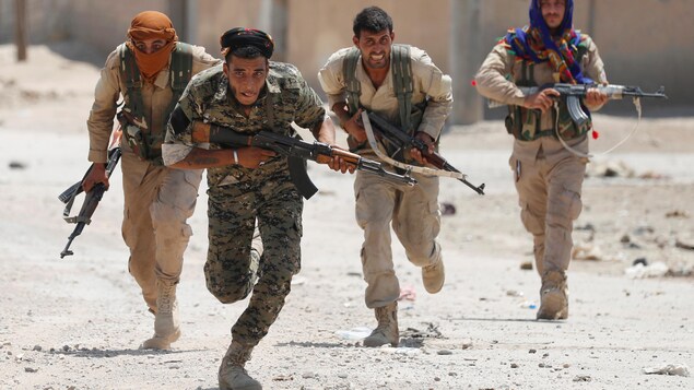 Quatre combattants des YPG courent dans une rue de Raqqa, en juillet 2017.