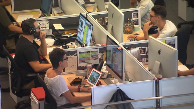 Periodistas frente a pantallas de ordenador en sus escritorios.