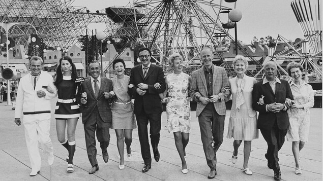 Les membres de l'équipe bras dessus, bras dessous, se promenant sur le site de La Ronde avec La Grande Roue en arrière-plan.
