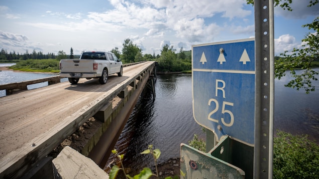 Une voiture traverse un petit pont au-dessus d'une rivière.