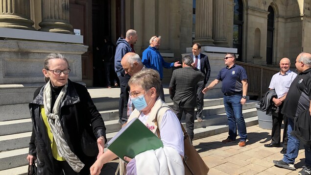 La mairesse Roseline Pelletier s'éloigne d'un groupe de personnes debout dans les marches de l'édifice de l'Assemblée législative.