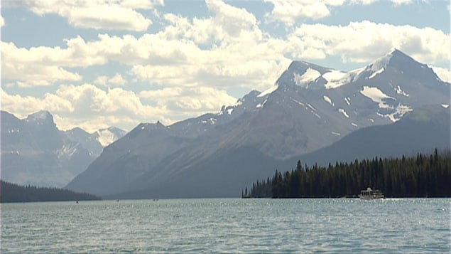 Des montagnes des Rocheuses surplombent le lac Maligne et un bateau en Alberta