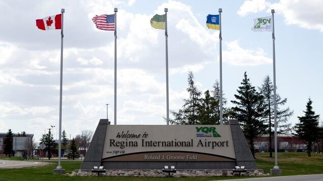 Vue de l'entrée de l'aéroport international de Regina avec des drapeaux qui flottent.