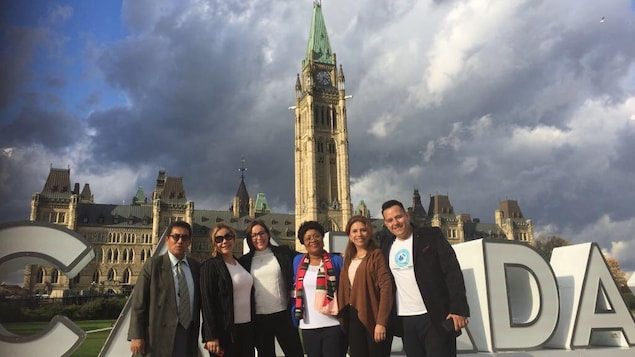 Des personnes posent devant le Parlement canadien