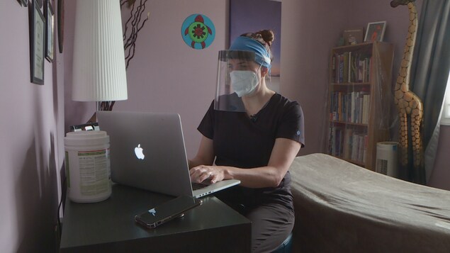 Laura Barr assise face à un ordinateur dans son clinique d'Edmonton.