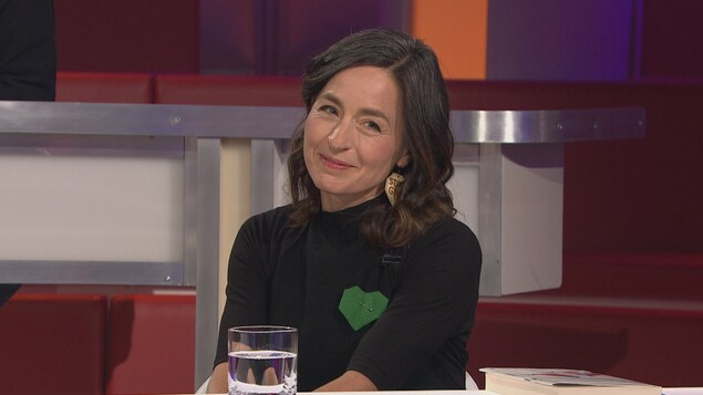 Elle porte un coeur vert sur son chandail.